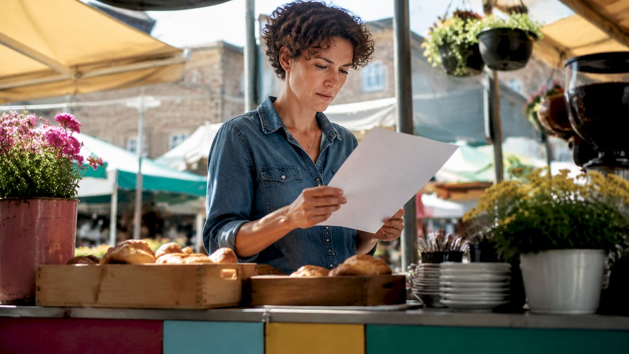 Café owner reviewing payment checklist at counter